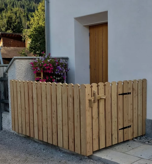 Ein Tor mit Zaun aus Lärchenholz, das den Eingangsbereich umschließt